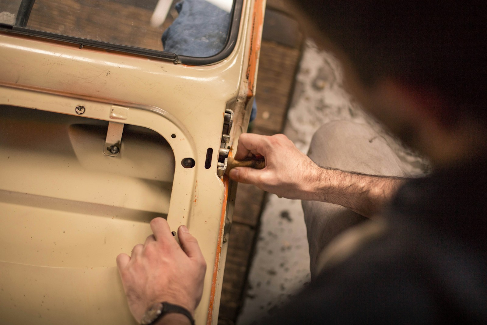 A man adjusting the lock mechanism on a car door how to choose an autobody shop